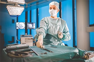 Chirurgische Fachkraft bereitet in einem modernen Operationssaal medizinische Instrumente für einen Eingriff vor.