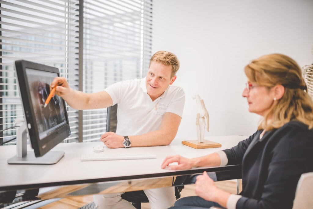 Orthopäde zeigt Patientin Untersuchungsergebnisse.