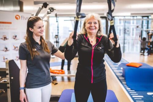 Patientin führt Training mit TRX Bändern aus und wird dabei ärztlich unterstützt