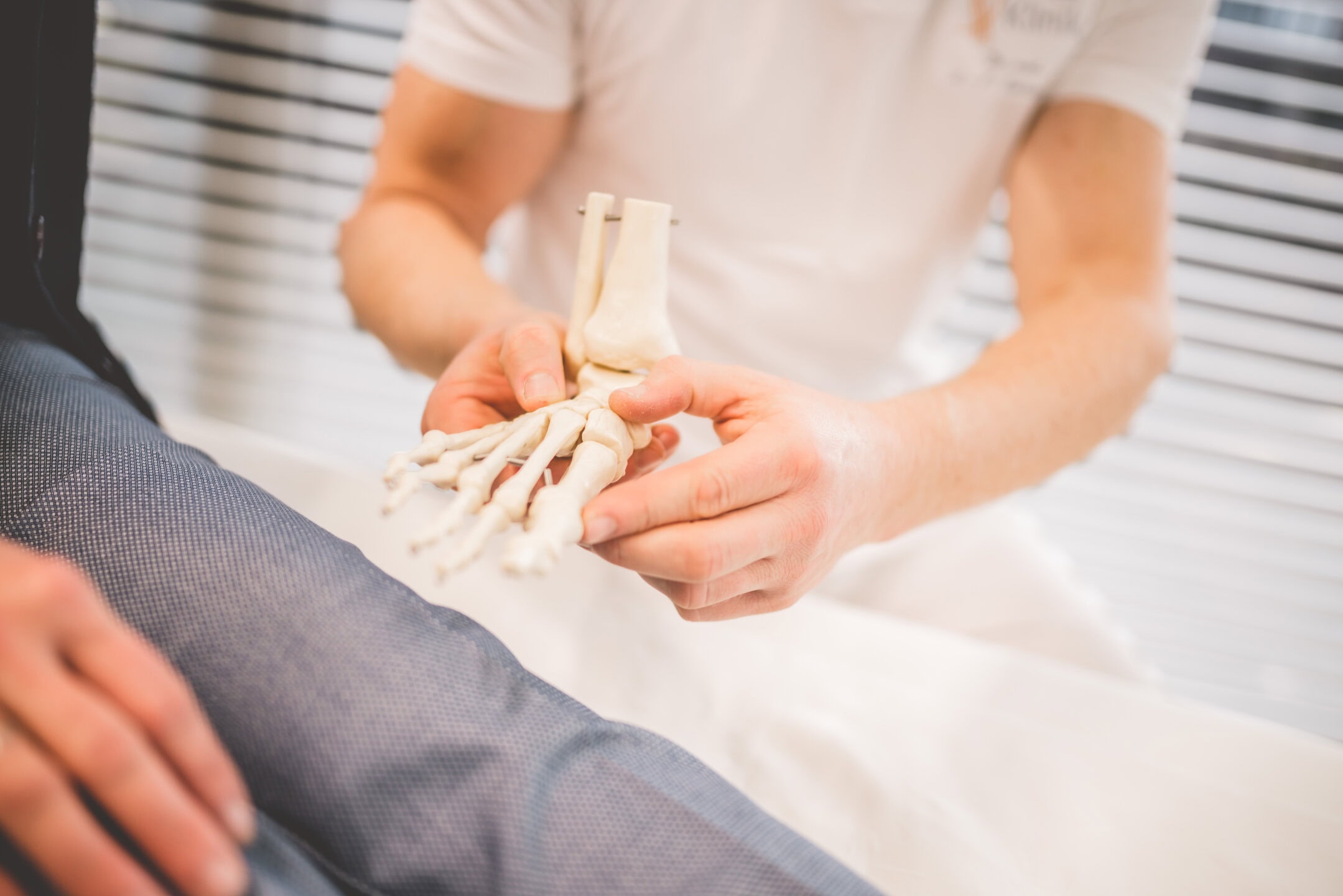 Ein Orthopäde zeigt das Modell eines Fußes.